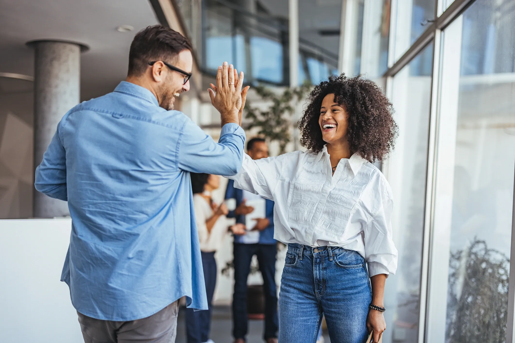 Two colleagues happily giving a high five at work.